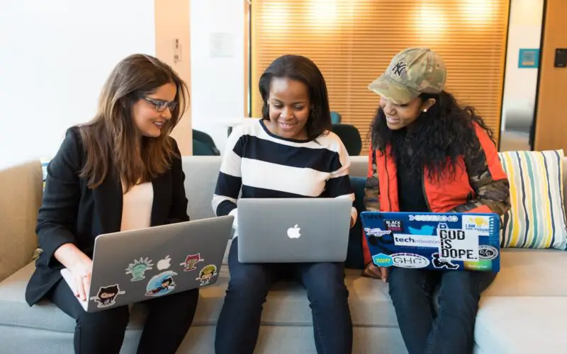 three women sitting on sofa with MacBook