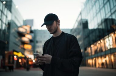 man in black jacket wearing black fitted cap while using phone